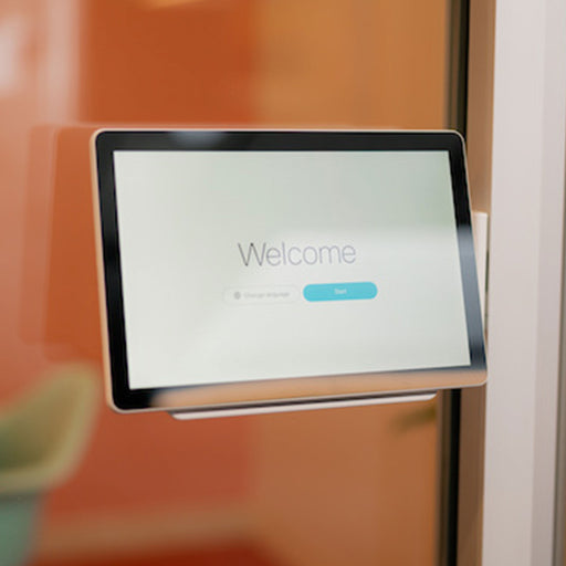 A Cisco Webex Room Navigator mounted on a white front bracket, displaying a welcome screen, mounted on a glass wall.